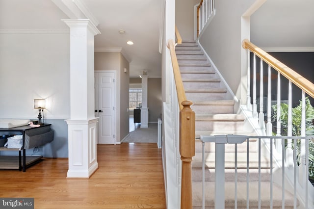 stairway featuring wood finished floors, recessed lighting, crown molding, baseboards, and ornate columns