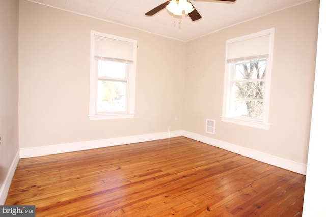 empty room with visible vents, ceiling fan, baseboards, and wood-type flooring