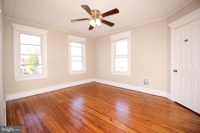 unfurnished room featuring baseboards, visible vents, wood-type flooring, and ornamental molding