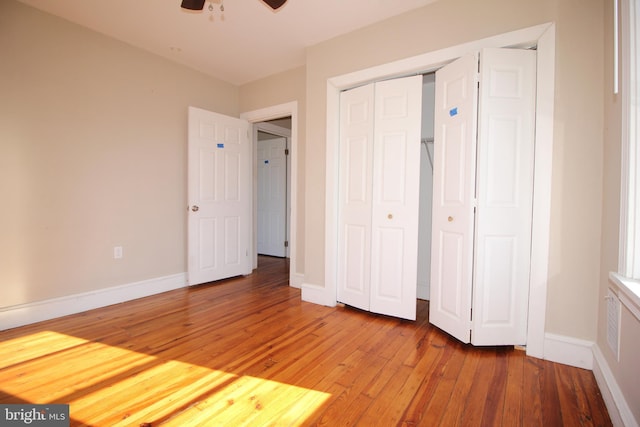 unfurnished bedroom with a closet, a ceiling fan, baseboards, and light wood finished floors