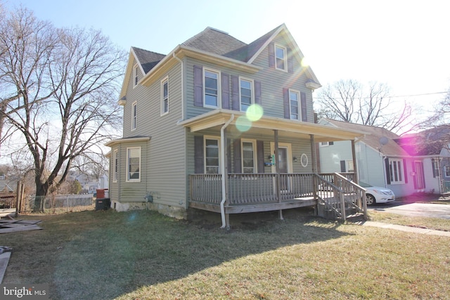 view of front facade with a porch, a front yard, and fence