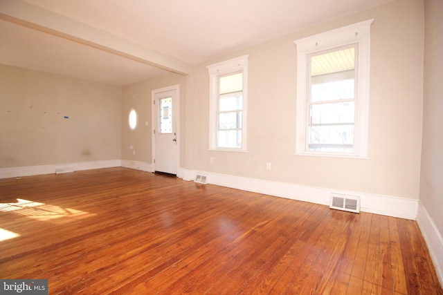 spare room with visible vents, baseboards, and wood-type flooring