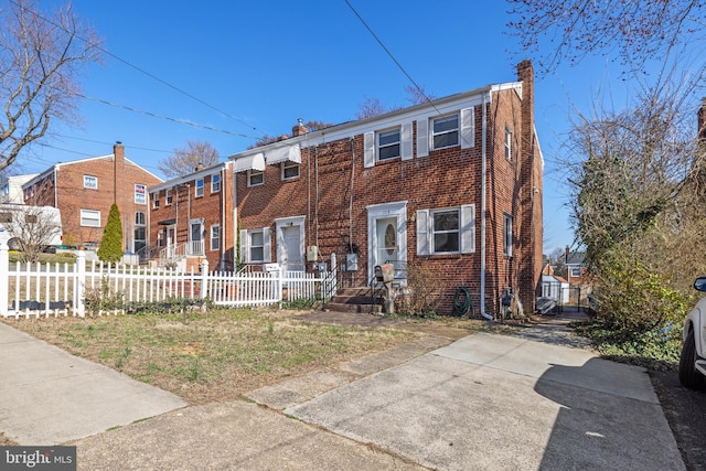 townhome / multi-family property with brick siding, a fenced front yard, and a chimney