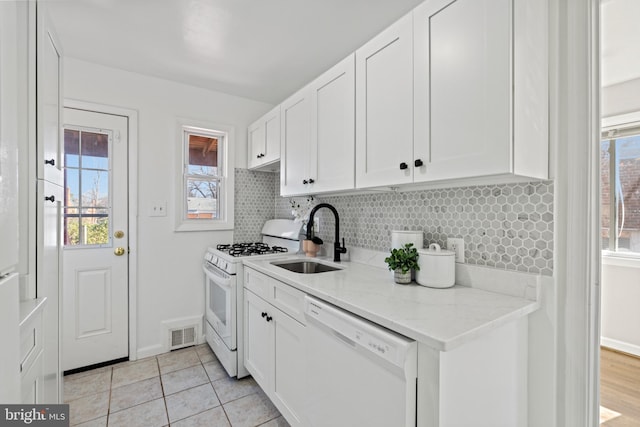 kitchen with visible vents, backsplash, white appliances, white cabinetry, and a sink