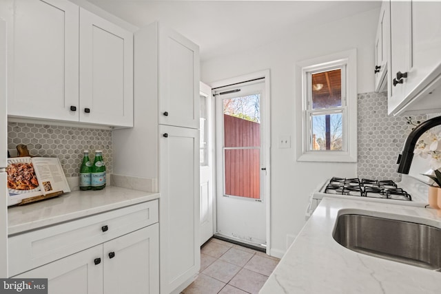 kitchen featuring light tile patterned floors, backsplash, white cabinetry, and light stone countertops