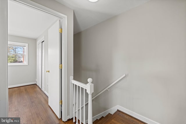 hall with wood finished floors, an upstairs landing, and baseboards