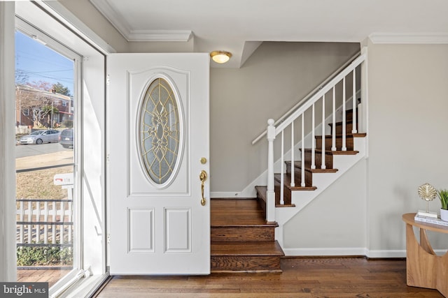 entryway with stairs, crown molding, wood finished floors, and baseboards