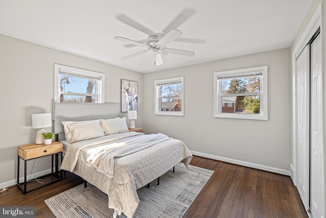 bedroom with a closet, a ceiling fan, dark wood-type flooring, and baseboards