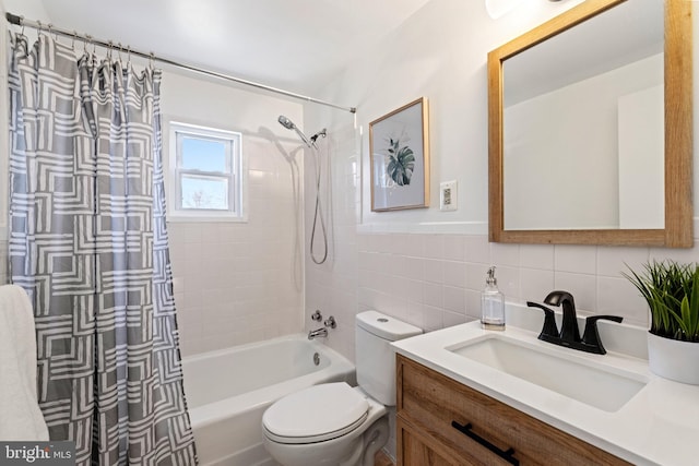 bathroom with vanity, tile walls, toilet, and shower / bath combo with shower curtain