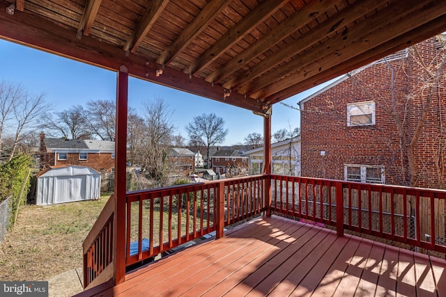 wooden terrace featuring a storage unit, a residential view, and an outbuilding