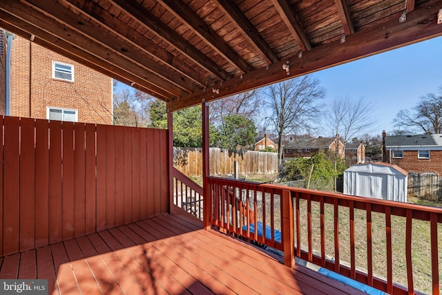 wooden terrace with a storage shed, an outbuilding, and a fenced backyard