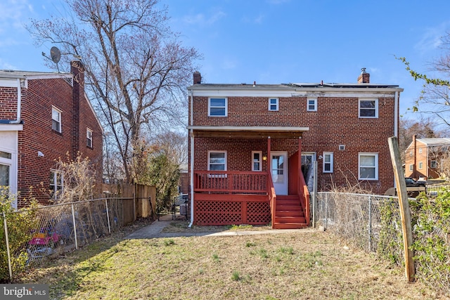 back of property with a chimney, a fenced backyard, brick siding, and a lawn