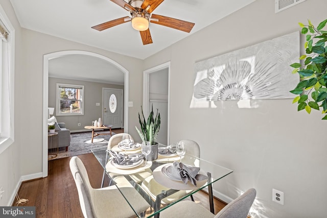 dining room with visible vents, wood finished floors, arched walkways, and baseboards