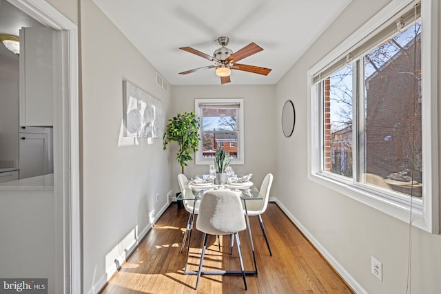 dining space with visible vents, baseboards, wood-type flooring, and ceiling fan