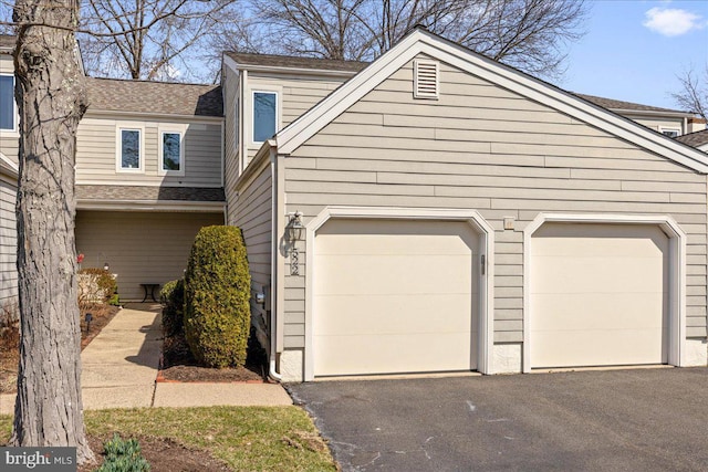 view of front of property featuring an attached garage, roof with shingles, and driveway