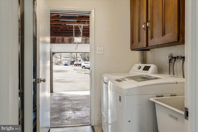 clothes washing area with a sink, cabinet space, and separate washer and dryer