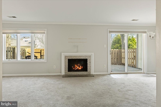 unfurnished living room featuring carpet flooring, plenty of natural light, a lit fireplace, and ornamental molding