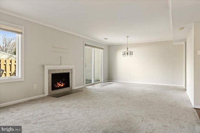 unfurnished living room featuring crown molding, a warm lit fireplace, a notable chandelier, and carpet floors