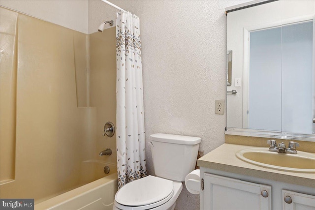 bathroom with shower / bath combination with curtain, toilet, vanity, and a textured wall