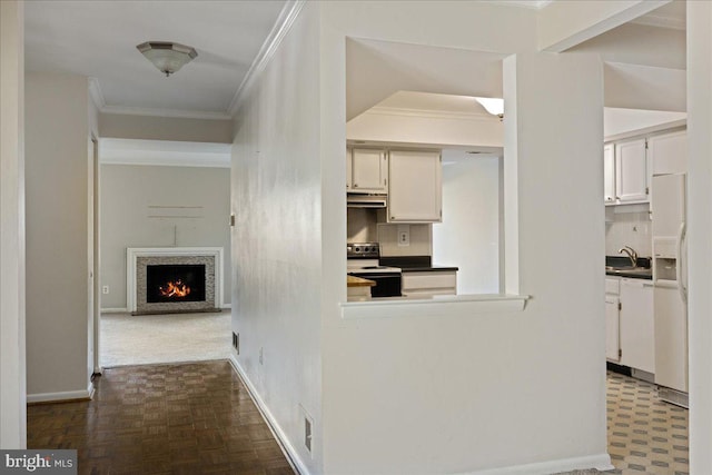 hallway featuring ornamental molding, baseboards, and a sink