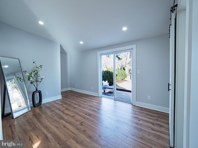 interior space with a barn door, recessed lighting, baseboards, and dark wood-style flooring