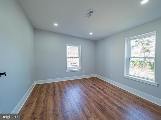 unfurnished room with dark wood-type flooring, recessed lighting, baseboards, and visible vents