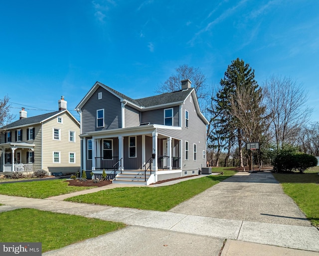 view of front of house with covered porch, concrete driveway, a front yard, central AC unit, and a chimney