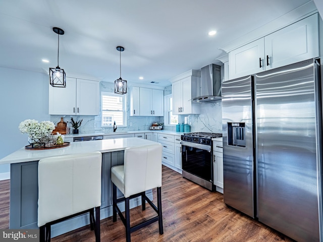 kitchen featuring light countertops, wall chimney exhaust hood, dark wood-style flooring, and appliances with stainless steel finishes