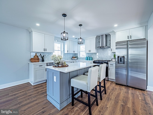 kitchen with backsplash, a center island, stainless steel appliances, white cabinets, and wall chimney range hood