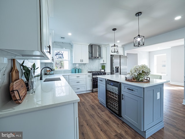 kitchen featuring dark wood-type flooring, beverage cooler, a sink, stainless steel appliances, and wall chimney range hood