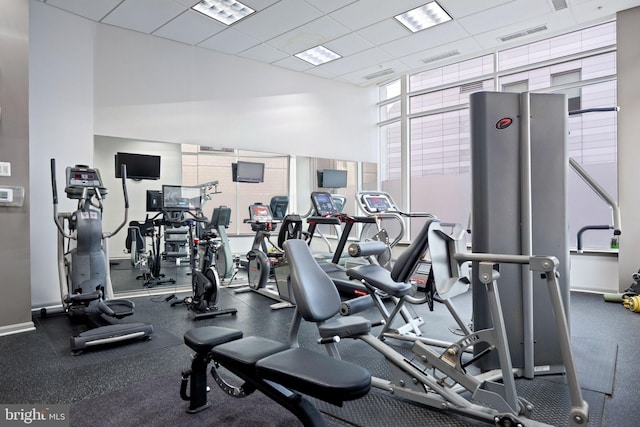 gym featuring a wall of windows, visible vents, a paneled ceiling, and baseboards