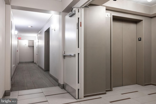 hallway featuring elevator and baseboards