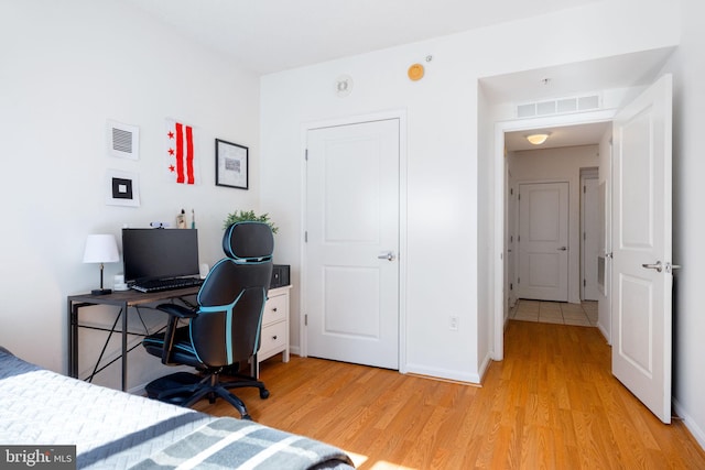 bedroom with baseboards, visible vents, and light wood finished floors