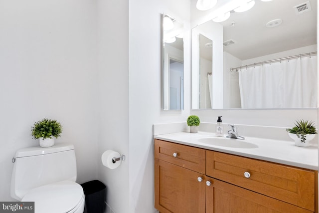 bathroom featuring vanity, toilet, and visible vents