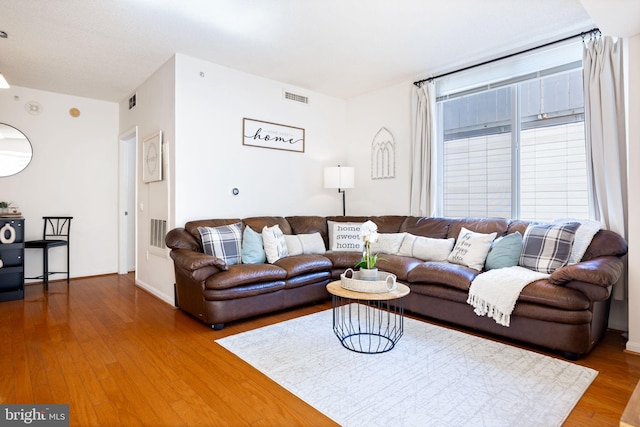 living area with wood finished floors, visible vents, and baseboards