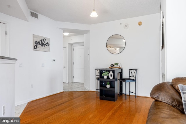 living area featuring light wood-type flooring, baseboards, and visible vents