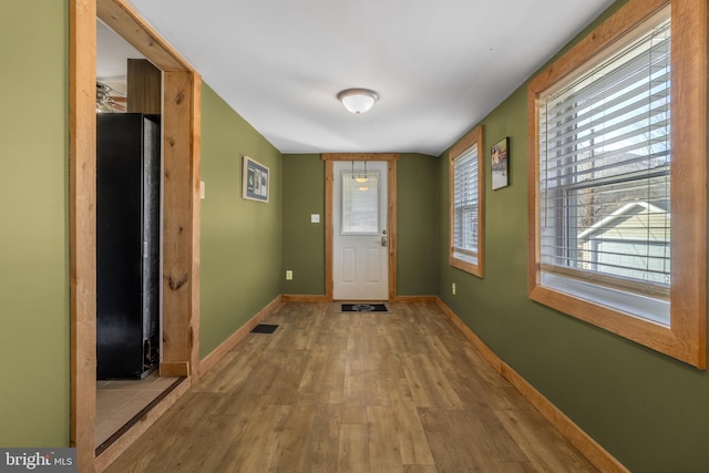 doorway to outside featuring visible vents, baseboards, and wood finished floors