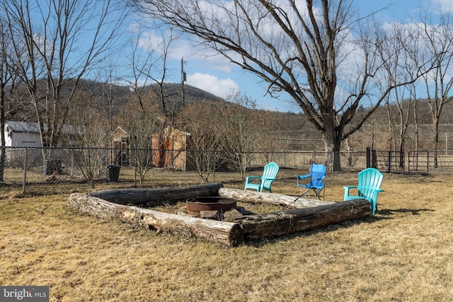 view of yard with a mountain view, a fire pit, and fence