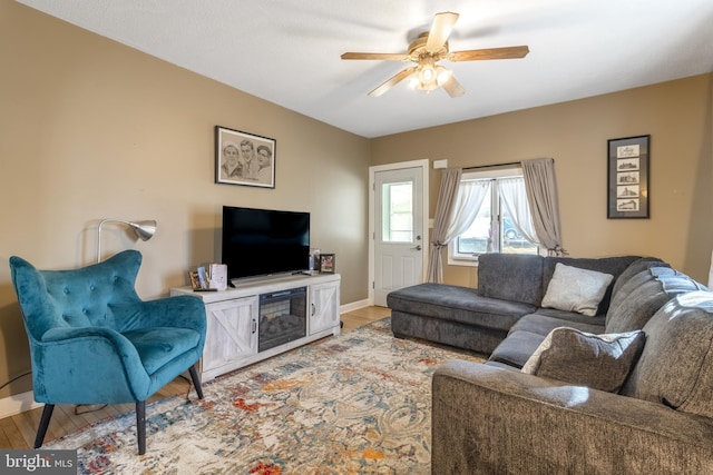 living room with baseboards, ceiling fan, and light wood finished floors