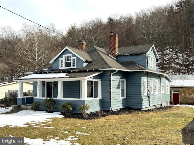 exterior space featuring a lawn, a chimney, and roof with shingles