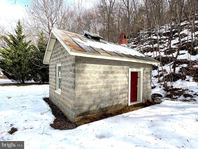 snow covered structure featuring an outbuilding