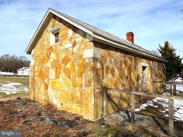 view of property exterior featuring stone siding and a chimney