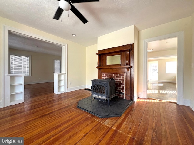 living room featuring hardwood / wood-style floors, a wood stove, and baseboards