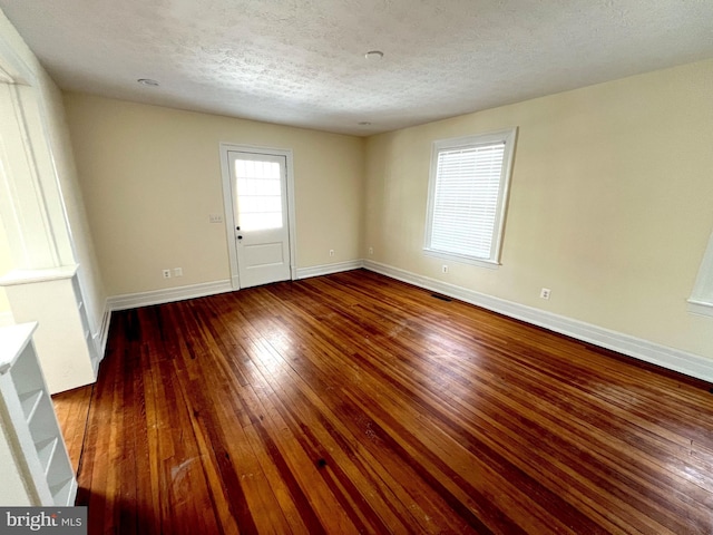 spare room with baseboards, wood-type flooring, and a textured ceiling