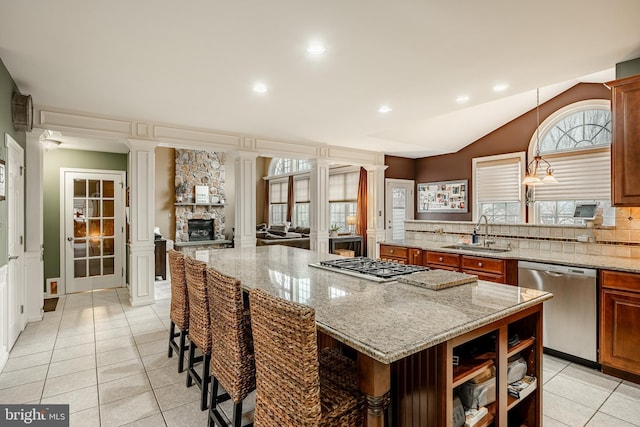 kitchen featuring ornate columns, a kitchen island, a sink, stainless steel appliances, and backsplash