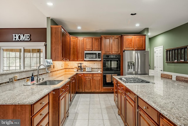 kitchen featuring a sink, light stone counters, tasteful backsplash, and appliances with stainless steel finishes