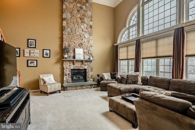 carpeted living area featuring a fireplace, crown molding, and a towering ceiling