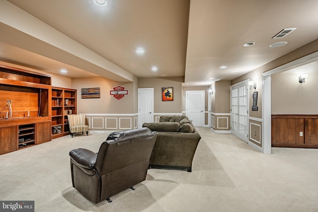 living room with recessed lighting, light colored carpet, and a wainscoted wall