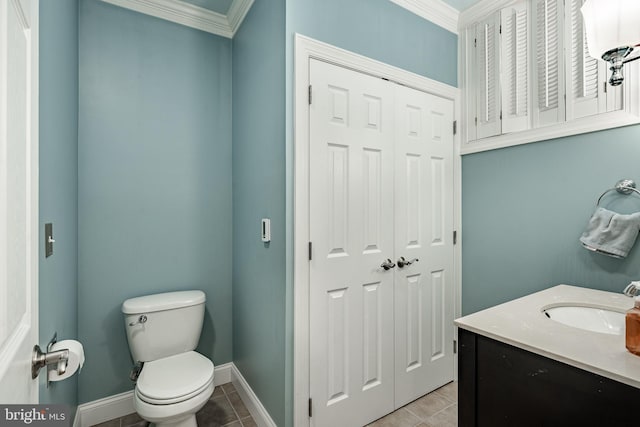 bathroom with vanity, baseboards, tile patterned flooring, crown molding, and toilet