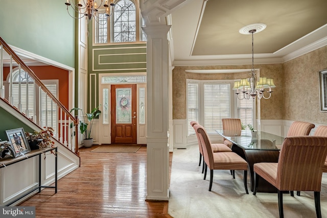 entrance foyer featuring an inviting chandelier, a wainscoted wall, a wealth of natural light, and ornamental molding